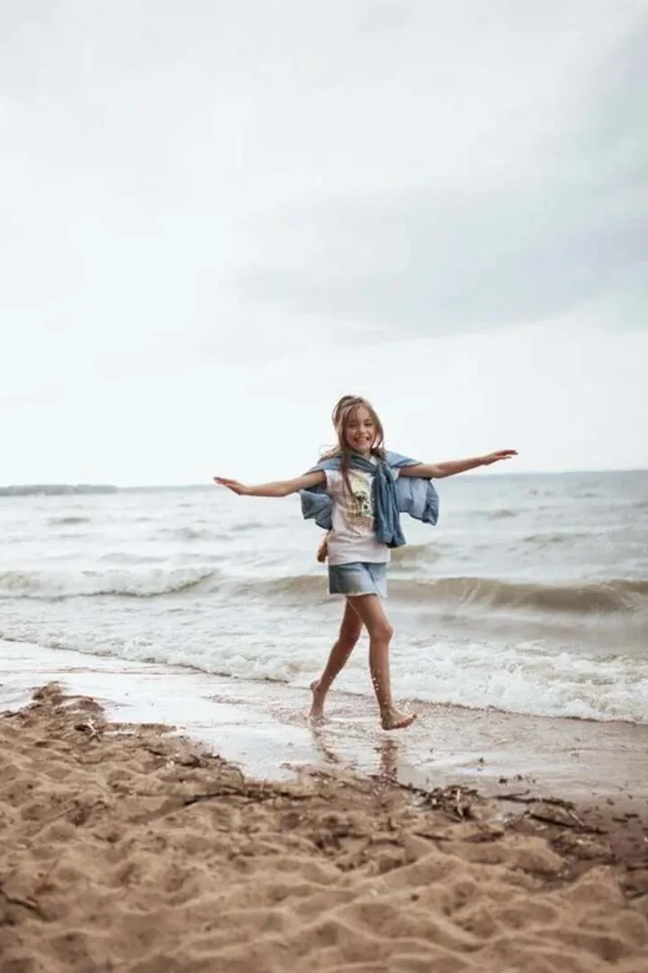 A person walking the shoreline with arms open